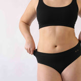 A woman wearing the Six Ada seamless underwear set in Black. Supportive and comfortable Bralette and high rise knicker style, suitable to wear for Maternity, breasfeeding, nursing bra, pregnancy and yoga.