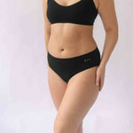 A woman wearing the Six Ada seamless underwear set in Black. Supportive and comfortable Bralette and high rise knicker style, suitable to wear for Maternity, breasfeeding, nursing bra, pregnancy and yoga.