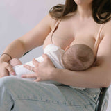 Woman sat breastfeeding her baby wearing the Ada ribbed seamless nursing bra from six in the blush nude colour.