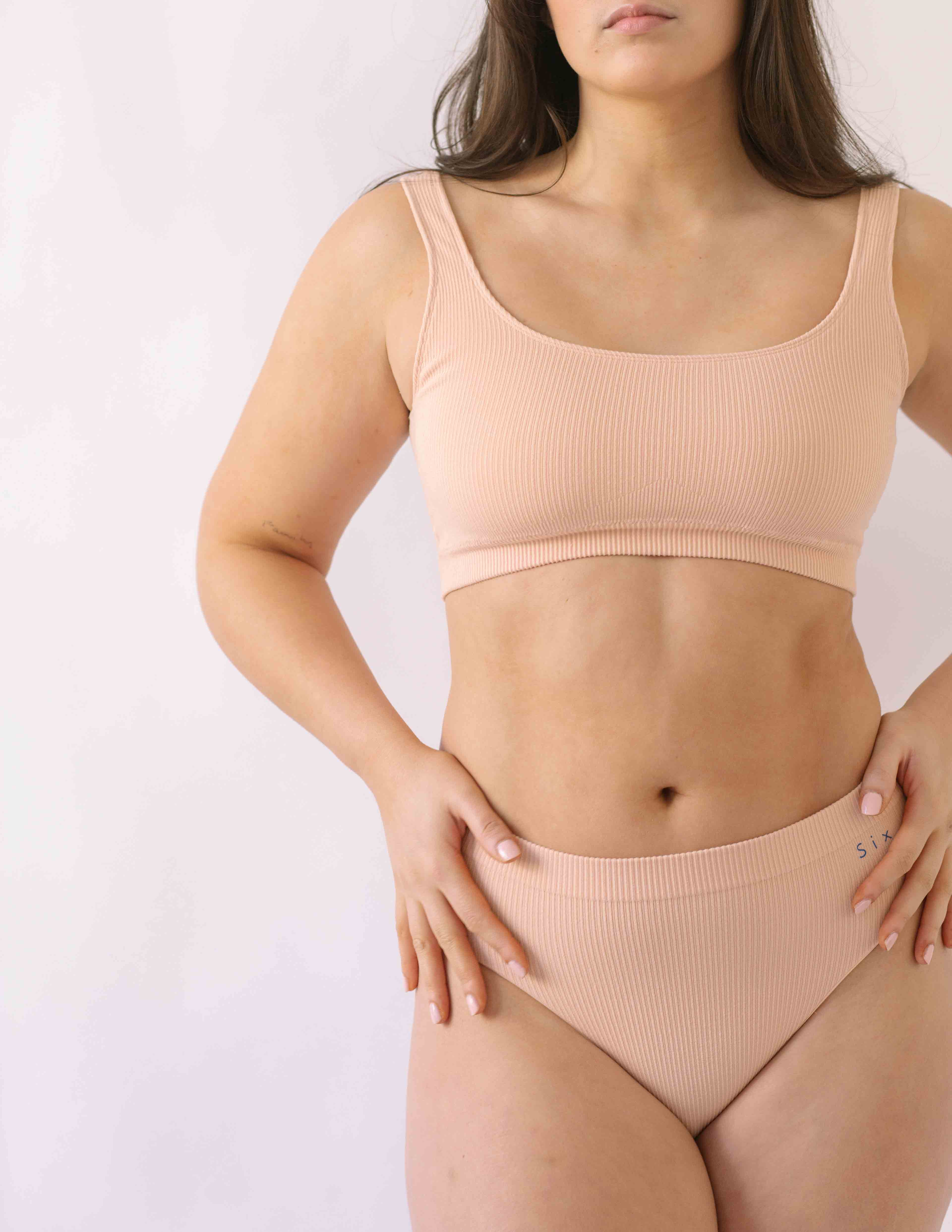 Woman wearing a set of Six seamless Ada underwear in Nude blush colour. A seamless supportive  and comfortable bralette  crop top and high waisted knicker suitable for post c-section, pregnancy and maternity Lingerie