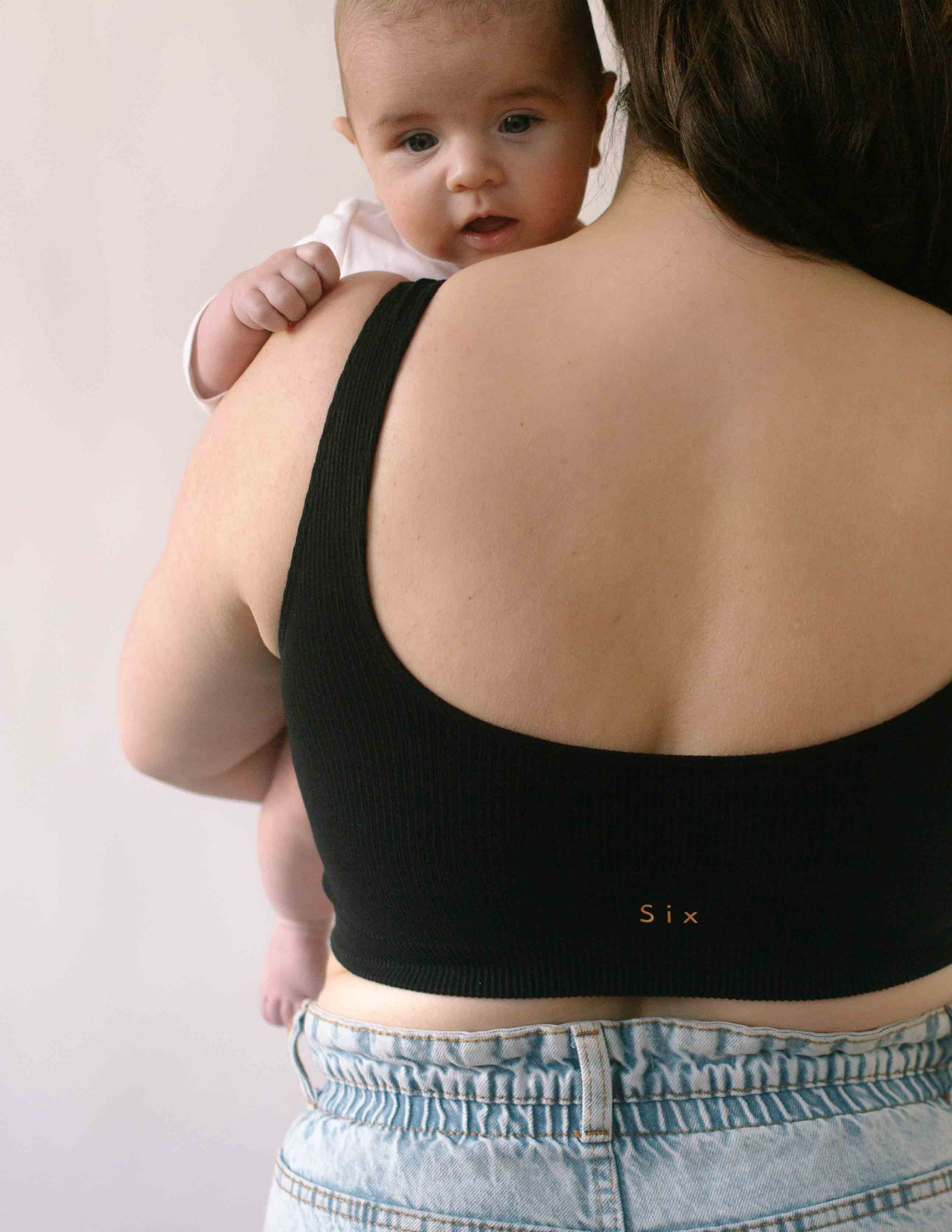 Woman holding a baby wearing the Six Maya Seamless comfortable and supporitve Bralette in Black