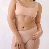 Woman wearing a set of Six seamless Ada underwear in Nude blush colour. A seamless supportive  and comfortable bralette  crop top and high waisted knicker suitable for post c-section, pregnancy and maternity Lingerie